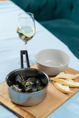 Boiled mussels with herbs and garlic sauce in a pot with a glass of white wine and crunchy croutons