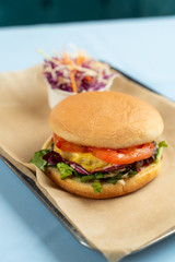 Juicy cheeseburger with vegetables and coleslaw on craft paper background