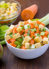 Vitamin salad of celery stalks, carrots, apples and cheese. Vegetable salad with cheese cut into cubes in a plate and a number of ingredients are.