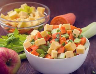 Vitamin salad of celery stalks, carrots, apples and cheese. Vegetable salad with cheese cut into cubes in a plate and a number of ingredients are.