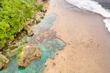Natural pools on the rocky shore with tourists formed at low tide. Magpupungko natural rock pools. Siargao, Philippines.