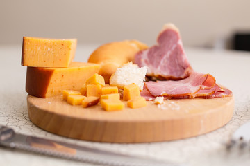 Ham, cheese and bread on a wooden cutting board. The breakfast in the village. Snack with beer or wine.