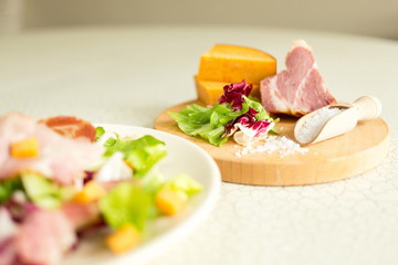 A plate of salad of green leaves, ham and cheese. Plate of salad with green leaves, ham and cheese. Fresh lettuce, cheese, ham and sea salt on a cutting board. Intercontinental breakfast at the hotel.