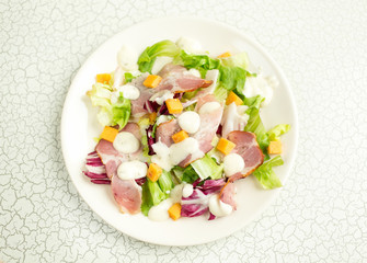 A plate of salad with green leaves, ham, cheese and white sauce. Intercontinental breakfast at the hotel. Dietary lunch. Food for Health.