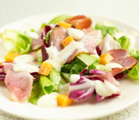A plate of salad with green leaves, ham, cheese and white sauce. Intercontinental breakfast at the hotel. Dietary lunch. Food for Health.