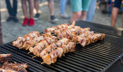Delicious bbq grilling meat on open grill, outdoor kitchen. Food festival in city. tasty food roasting on skewers, food-court. Summer picnic.