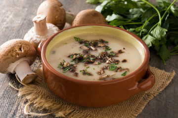 Homemade mushroom soup in bowl on wooden table. 