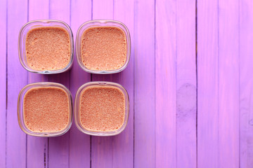 Obraz na płótnie Canvas Chocolate milk dessert on a violet wooden background - four portions. Flat lay.