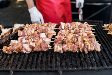 Delicious bbq grilling meat on open grill, outdoor kitchen. Food festival in city. tasty food roasting on skewers, food-court. Summer picnic.