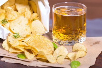 Potato chips with salt and greens on a table in a pub on a background of beer. Chips with greens as...