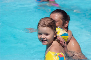 Happy father and daughter playing in the swimming pool; summertime background