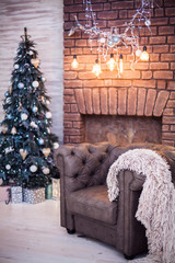 Leather chair Chester with plaid in front of the Christmas tree and a classic high stone fireplace. Vertical