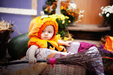 Child in Halloween costume. Kids trick or treat. Little boy with pumpkin lantern. Baby in witch hat. Autumn season holiday decoration. Home festive interior with fall leaves and squash.