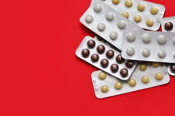 Set of pills blisters isolated on solid red background. Medical concept.  Potent drugs. White, brown and yellow pills.