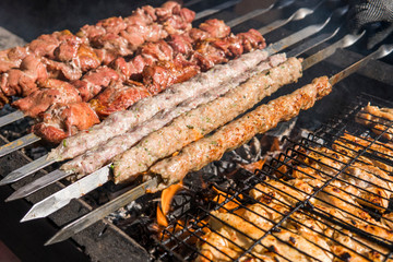 Delicious bbq grilling meat on open grill, outdoor kitchen. Food festival in city. tasty food roasting on skewers, food-court. Summer picnic.