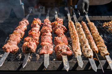 Delicious bbq grilling meat on open grill, outdoor kitchen. Food festival in city. tasty food roasting on skewers, food-court. Summer picnic.