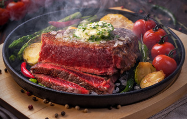 Roasted beef steak medium rare with butter and a vegetable side dish.