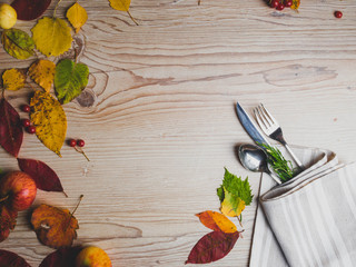 Fototapeta na wymiar Fall or autumn themed place setting with a knife, spoon and fork, napkin on a plate on an arrangement of colorful leaves, copy space for text