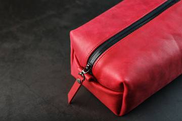 Naklejka premium Bag for cosmetics and jewelry made of genuine red leather, on a dark background. Handwork.
