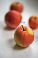 five ripe apples, red with yellow spots, lie on a white table