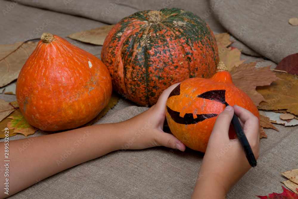 Wall mural the child draws a pumpkin face on a black market, jack o lantern, halloween background, preparation 