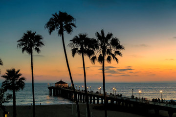 Obraz premium Palmy o zachodzie słońca na plaży w Kalifornii. Manhattan Beach, Los Angeles.