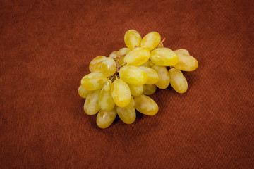 Light grapes on brown background. Grapes on brown velvet fabric.