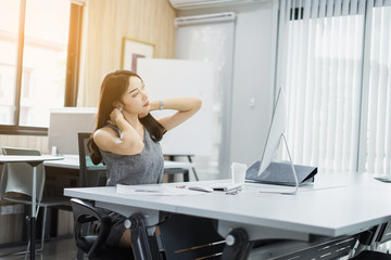 Concentrated young businesswoman working and have pains and aches on her computer in the office.,sitting on workplace.