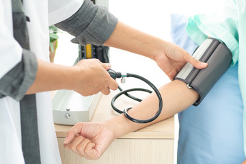 Doctor checking blood pressure of patient at the hospital .