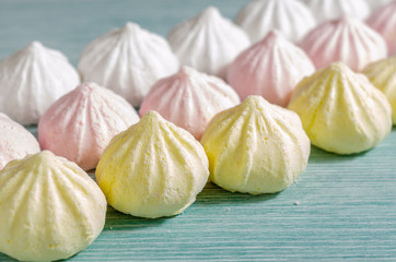 Mini meringues of pastel colors on light blue background