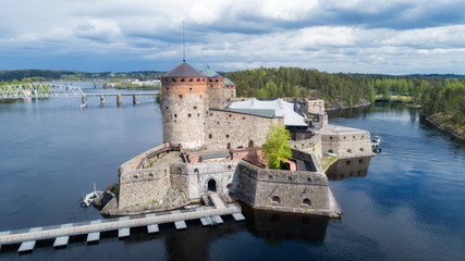 Fototapeta na wymiar Beautiful aerial view of Olavinlinna, Olofsborg ancient fortress. Tower castle located in Savonlinna city on a cloudy summer day with dramatic sky. Finland. Drone photography from above.