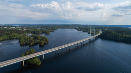 Fototapeta na wymiar Aerial view of blue lakes, green forests and bridge. Sunny summer day in rural Finland. Drone photography from the air.