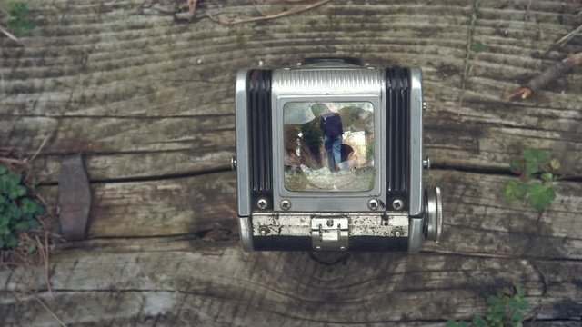 First person view through vintage TLR (Twin lens reflex) camera viewfinder. Old vintage film camera. The camera on a vintage background. Focus on the image, the girl goes on rails with a dog.