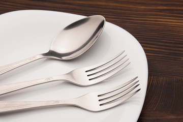 Fork And spoon on Plate On wood table . Dishes and cutlery. 