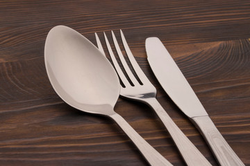 Cutlery Set. Spoon, Fork, Knife on a dark wood background. close up 