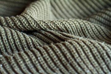 Close-up olive color knitted sweater made of natural wool texture, wavy folds, selective focus