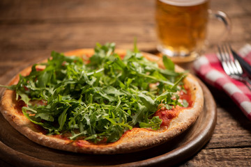 Italian Pizza with tomatoes, mozzarella cheese and arugula on wooden cutting board