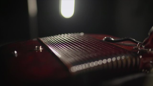 Close-up musician playing the accordion against a black background. playing the button accordion in the studio