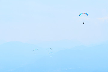 Naklejka na ściany i meble Paraglider flying over the Garda Lake (Lago di Garda or Lago Benaco). Paragliding on Monte Baldo. Panorama of the gorgeous Garda lake surrounded by mountains, Malcesine, Italy