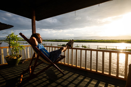 a man is relaxing at wooden cottage in inle lake