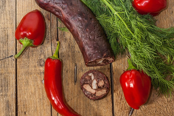 Black sliced pudding on a shabby wooden table with red bell pepper. Top view