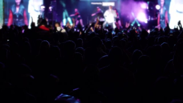 people in fan zone dance to band performing on stage