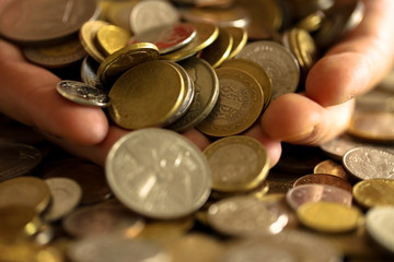 many coins of different countries in the hands of close-up