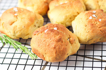 homemade fresh herb bread rolls of Provencal herbs with salt and a sprig branch of rosemary. Bread rolls bakery style on the cooling wrack