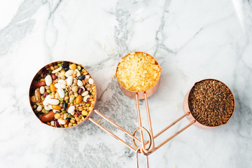 Copper measuring cups on marble table in the kitchen. Ready to cook or bulk food purchase concept. Flat lay