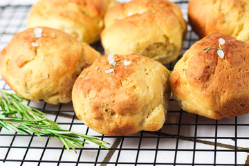 homemade fresh herb bread rolls of Provencal herbs with salt and a sprig branch of rosemary. Bread rolls bakery style on the cooling wrack