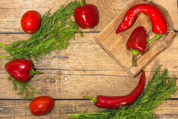 Healthy eating background. Juicy ripe bell sweet peppers and hot chili peppers with dill on an old wooden table