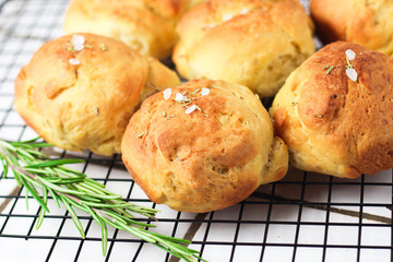 homemade fresh herb bread rolls of Provencal herbs with salt and a sprig branch of rosemary. Bread rolls bakery style on the cooling wrack