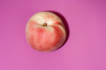 Juicy ripe peach on a pastel pink background with a hard shadow