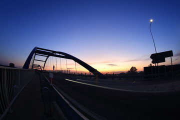 Most wiszący nad autostradą po zachodzie słońca, samochody. © Stanisław Błachowicz